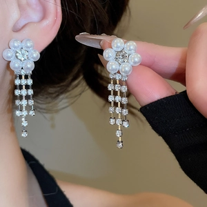 Detailed close-up of long silver fringe earrings with crystal flowers and white pearls