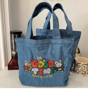 Detailed embroidery of cartoon rabbits and text on large denim tote bag surface