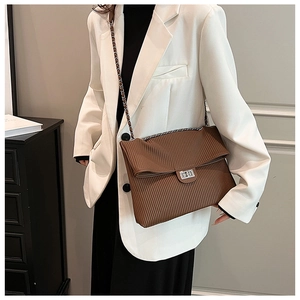 Borsa a pieghe marrone con catena e chiusura in metallo indossata con blazer bianco