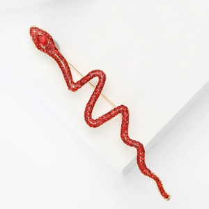 Luxury snake shaped brooch with red rhinestones on gold metal base over white background