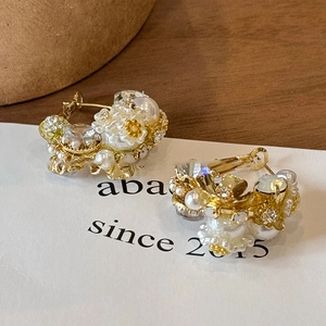Macro detail of vintage gold hoop earrings with white pearls and sparkling crystals