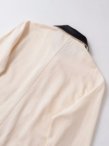 Détail de veste utilitaire crème avec col en cuir noir et texture en toile de coton robuste
