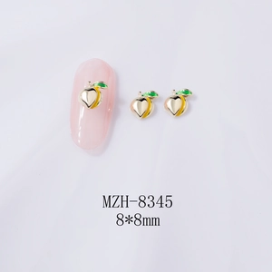 Macro shot of 8x8mm peach-shaped alloy nail art charms with gold finish and green leaves