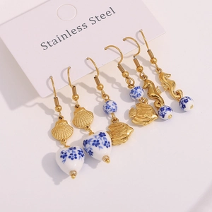 Detail of 18K gold stainless steel earrings with blue ceramic heart and shell charms