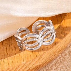 Macro detail of silver hollow leaf ring with woven texture on a wooden tray