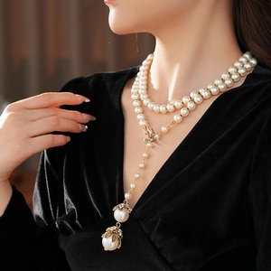 Detail of layered pearl necklace featuring a golden bow and elegant tassel pendant