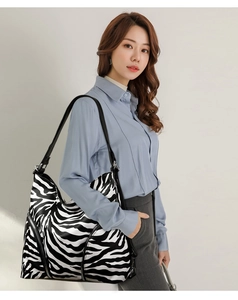 Fashionable zebra print tote bag shown being worn by a model on a white background