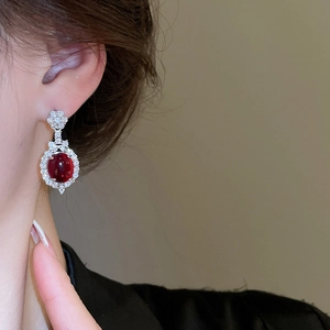 Macro detail of oval ruby earrings with silver settings and diamonds worn by model