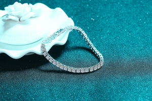 Macro detail of 925 sterling silver tennis bracelet with brilliant cut stones on teal glitter