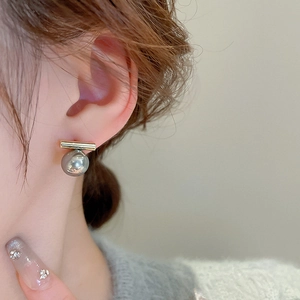 Primo piano di orecchini a barra dorata con perle indossati da una modella elegante