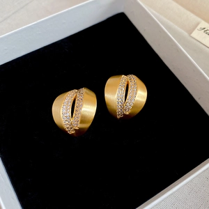 Detailed macro view of 18K brushed gold C-shaped studs with double rows of zircon inlay