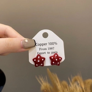 Red star stud earrings with white polka dots on copper base shown on display card