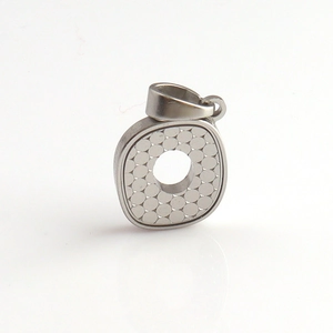 Dettaglio del ciondolo a forma di O in metallo argento con texture a nido d'ape