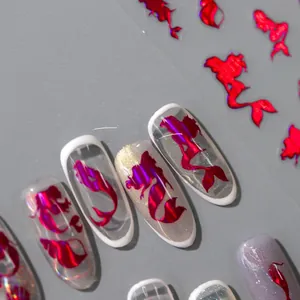 Macro detail of red laser mermaid and koi nail art stickers with metallic gold finish