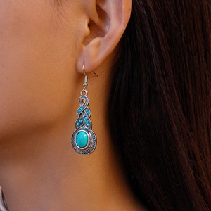 Detail of vintage leaf earring with turquoise stone worn by model in a natural setting