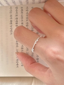 Macro shot of a 925 sterling silver bow knot open ring worn on a finger over a book