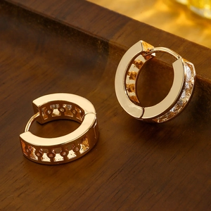 Gold plated geometric hoop earrings with clear cubic zirconia on a dark wood background
