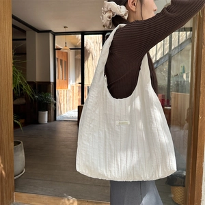 Detail shot of white pleated tote bag showing the vertical texture and Sczakka label