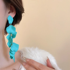 Detailed close-up of blue petal-shaped drop earrings worn by a model in a fashion setting