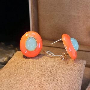 Macro shot of French vintage oval enamel earrings with orange and light blue finish