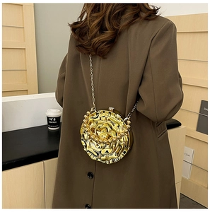 Detail of a 3D gold rose-shaped evening bag with metal chain worn over a brown coat