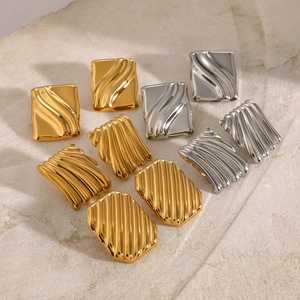 Detailed view of irregular geometric square earrings with wavy textures in gold and silver
