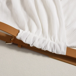 Macro detail of white pleated fabric texture with brown leather belt and buckle