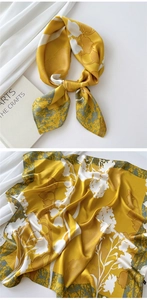 Detail of golden silk scarf with white floral print and artistic grey textured edges