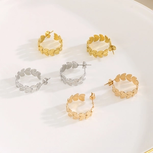 Detail view of gold and silver wheat leaf hoop earrings on a white display plate