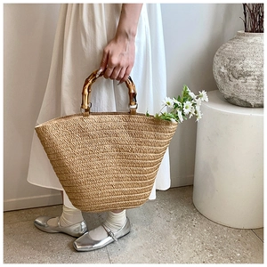 Detail of straw woven tote bag featuring bamboo handles and rustic fiber texture