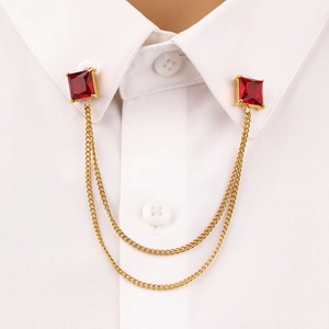 Detail of gold collar pins with red square stones and delicate chains on a white shirt