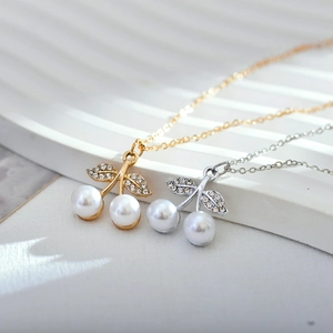 Detailed view of cherry pendant necklaces with white pearls and sparkling rhinestones