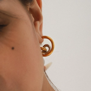 Minimalist gold and silver two-tone curved line earrings worn by a model in a close-up view