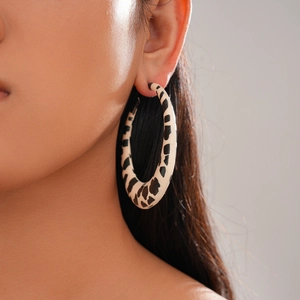 Close-up of lightweight leopard print resin hoop earrings on a model with neutral tones