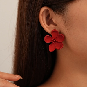 Close-up of model wearing matte red five-petal flower stud earrings with a vintage style