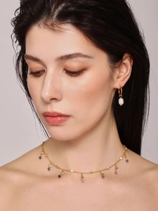 Detail of gold necklace with lapis lazuli and pearls worn by a model in soft lighting