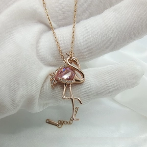 Detailed macro of flamingo pendant featuring a pink pear-cut gem and zircon accents