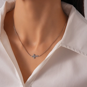 Close-up of minimalist silver cross pendant necklace on a model with box chain detail