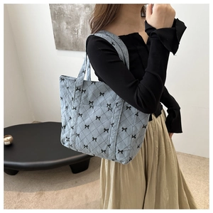 Detail of light blue quilted corduroy tote bag featuring a black bow pattern design