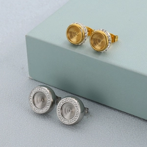 Detail of round stud earrings with concentric rings and crystal halo in gold and silver