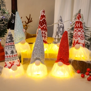 Close-up of glowing Christmas gnomes with knit hats and warm LED lights for holiday decor