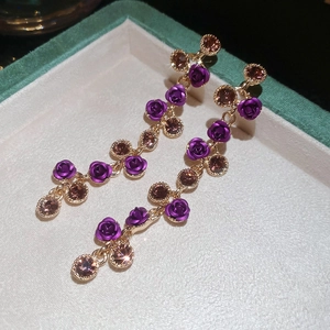 Detail of rose tassel earrings with purple flower pendants and sparkling brown crystals