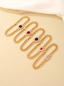 Close-up of five gold plated Cuban link bracelets with colorful oval zircon gemstones