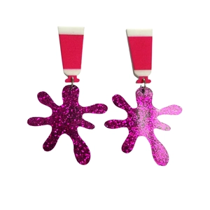 Creative pink acrylic earrings featuring paint tube and glitter splatter designs