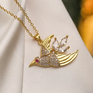 Primer plano del collar con colgante de pájaro dorado y gemas sobre seda blanca