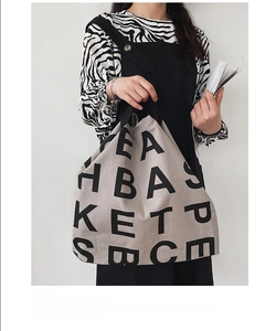 Detailed shot of beige canvas tote bag with bold black typography and slogan text