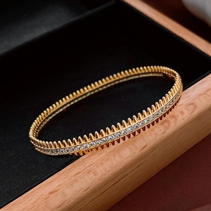 Détail d'un bracelet doré avec oxydes de zirconium et texture cloutée sur écrin velours