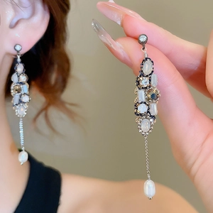 Detail view of long tassel earrings with sparkling zircons and pearls on silver needles