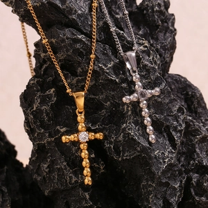 Detail of cross pendant featuring gold and silver finish with central white zircon