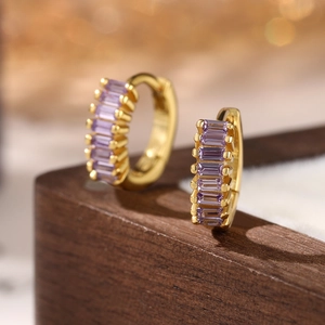 Macro shot of 925 silver huggie hoop earrings with purple zircon in gold plating